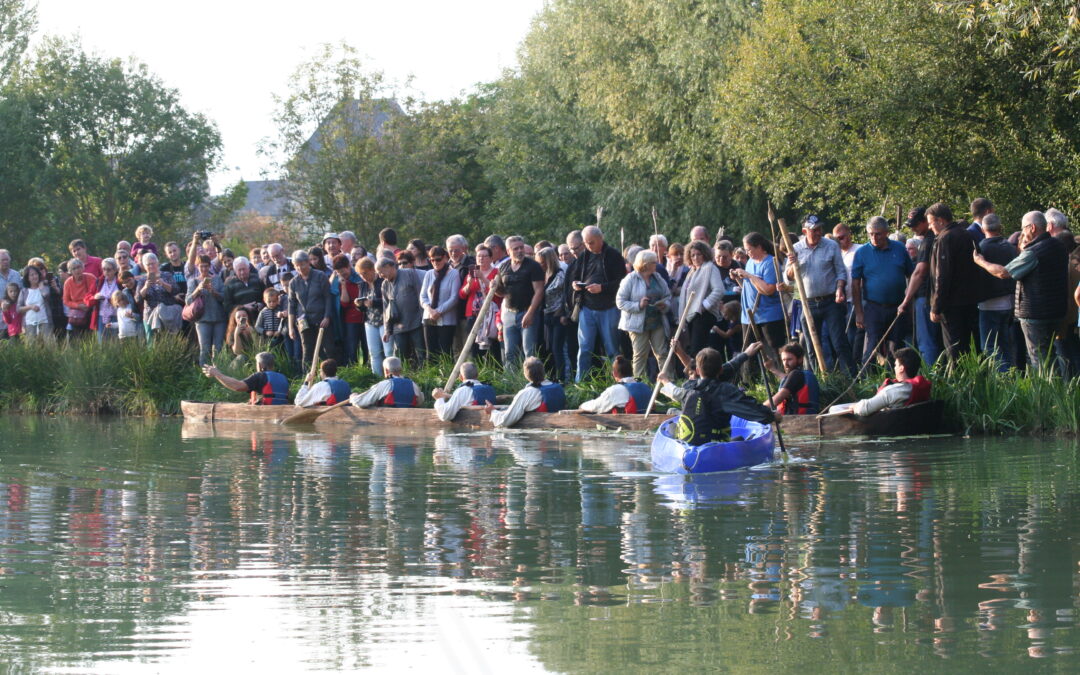 spectateurs sur la rive regarde un équipage sur une pirogue monoxyle