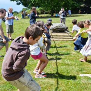 Des enfants déplacent un menhir sur des rondins de bois