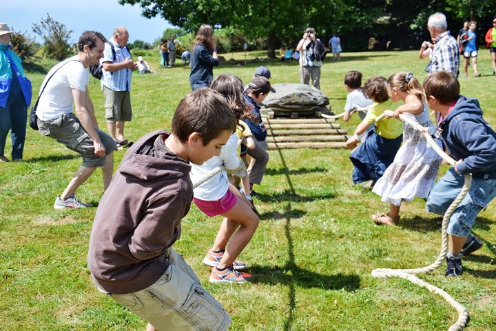 Des enfants déplacent un menhir sur des rondins de bois